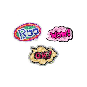 Könnte beinhalten: Drei bunte Bügelbilder mit den Worten "Boo", "Wow!" und "Ok!" in einem Sprechblasendesign. Die Patches sind aus Pailletten gefertigt und eignen sich perfekt, um Kleidung, Taschen oder anderen Accessoires eine lustige und skurrile Note zu verleihen.