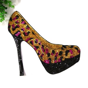 Peut inclure: Une chaussure noire à talon haut avec un motif de sequins léopard or et rose.