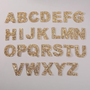 May include: Gold glitter alphabet letters, A through Z, on a white background.