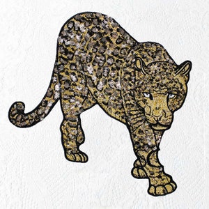 Könnte beinhalten: Ein gold- und schwarzfarbener Pailletten-Aufnäher mit einem Leopardenmotiv. Der Leopard blickt nach vorne, der Kopf ist leicht nach rechts gedreht. Der Aufnäher ist perfekt, um Kleidung, Taschen oder anderen Accessoires einen Hauch von Wildheit zu verleihen.