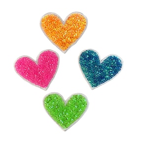 Puede incluir: Cuatro parches en forma de corazón con adornos de lentejuelas en naranja, rosa, azul y verde.
