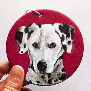 May include: A hand-painted ceramic ornament featuring a Dalmatian dog with black spots on a red background.