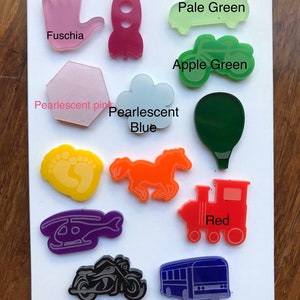 May include: A collection of colorful acrylic shapes, including a hand, rocket, car, cloud, horse, train, helicopter, motorcycle, and bus. Colors include fuchsia, hot pink, pale green, apple green, pearlescent pink, pearlescent blue, orange, red, and dark blue.