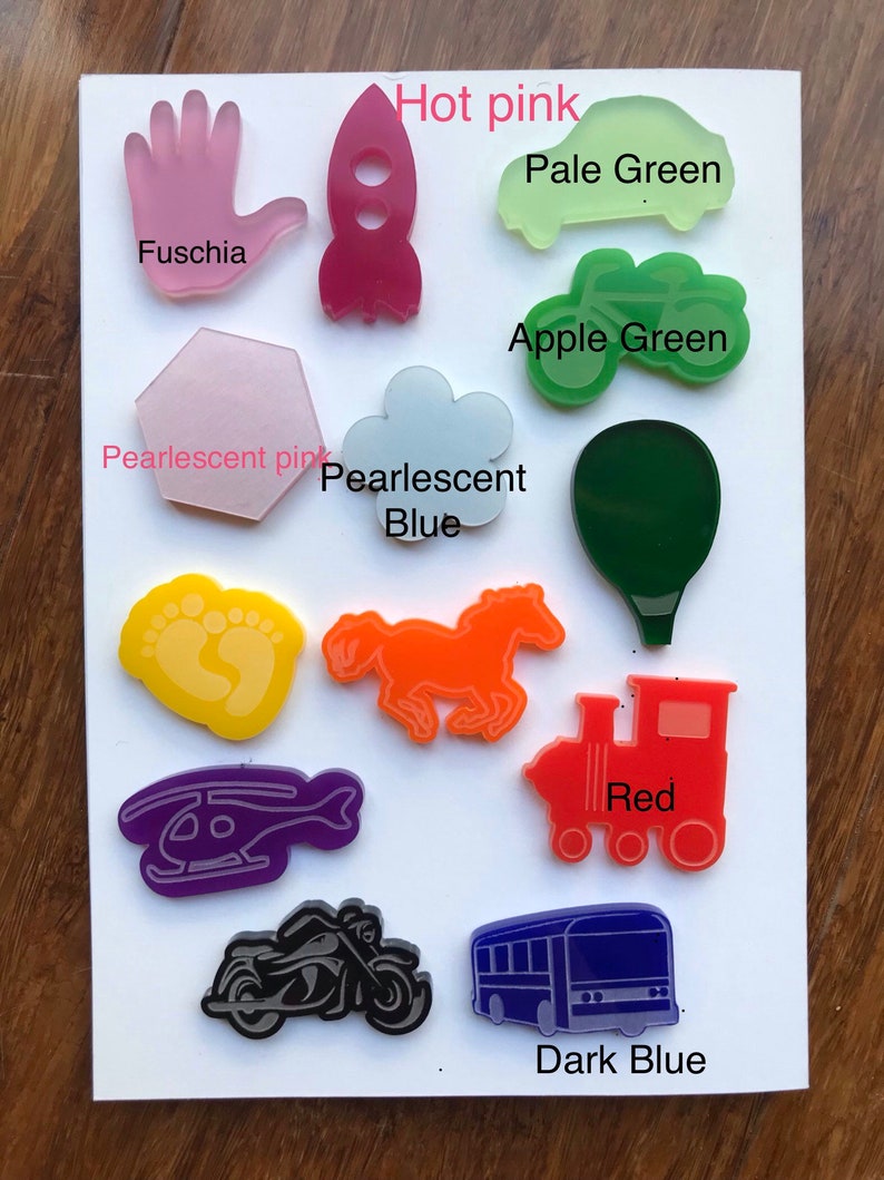 May include: A collection of colorful acrylic shapes, including a hand, rocket, car, cloud, horse, train, helicopter, motorcycle, and bus. Colors include fuchsia, hot pink, pale green, apple green, pearlescent pink, pearlescent blue, orange, red, and dark blue.
