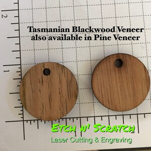 May include: Two round wooden pendants with a hole at the top, made from Tasmanian Blackwood Veneer. The pendants are light brown with visible wood grain. Text on the image reads "Tasmanian Blackwood Veneer also available in Pine Veneer" and "ETCH N' SCRATCH Laser Cutting & Engraving."