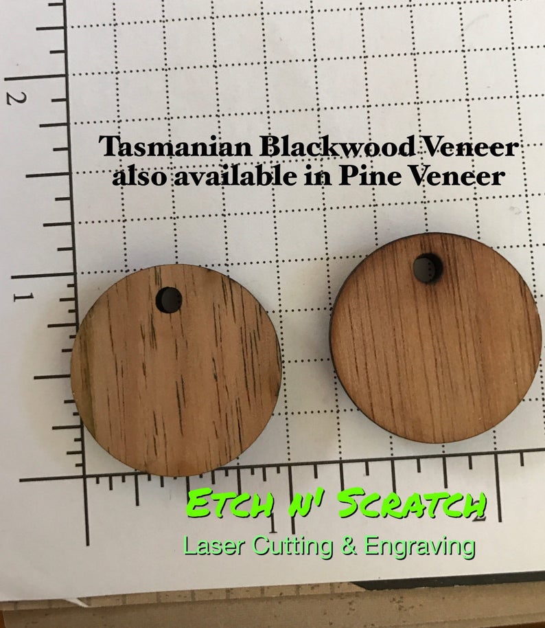 May include: Two round wooden pendants with a hole at the top, made from Tasmanian Blackwood Veneer. The pendants are light brown with visible wood grain. Text on the image reads "Tasmanian Blackwood Veneer also available in Pine Veneer" and "ETCH N' SCRATCH Laser Cutting & Engraving."