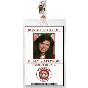 May include: A white plastic ID card with a photo of a woman with long brown hair. The card says "Bayside High School" and "Kelly Kapowski Student ID Card". The card also has a red and white logo with the words "Bayside Tigers".
