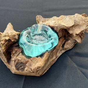 Pode incluir: Uma tigela de vidro azul-turquesa assenta em uma pe&ccedil;a natural e desgastada de madeira &agrave; deriva. A tigela tem uma forma &uacute;nica e org&acirc;nica e seria perfeita para uma vela ou uma planta pequena.