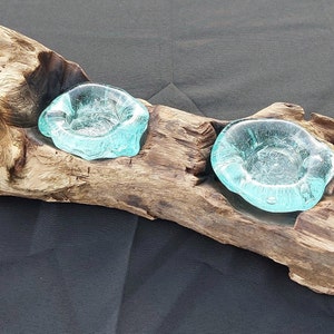 Pode incluir: Um porta-velas de madeira r&uacute;stico com dois copos de vela de vidro azul-esverdeado.