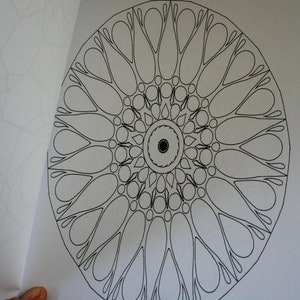 May include: A black and white mandala colouring page with a circular design featuring intricate details and a central circle.