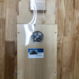 May include: A wooden birdhouse kit with a circular opening for the birds to enter. The kit is made of unfinished wood and comes with all the necessary hardware. The kit is packaged in a clear plastic bag with a business card for "Wooden Habitats" on the front.
