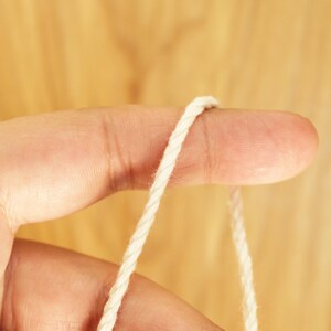 May include: A close-up of a white cotton cord wrapped around a finger.