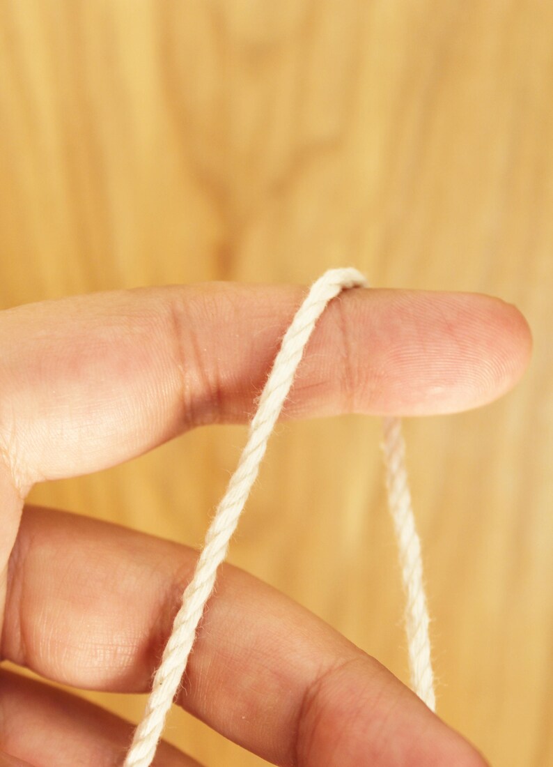 May include: A close-up of a white cotton cord wrapped around a finger.