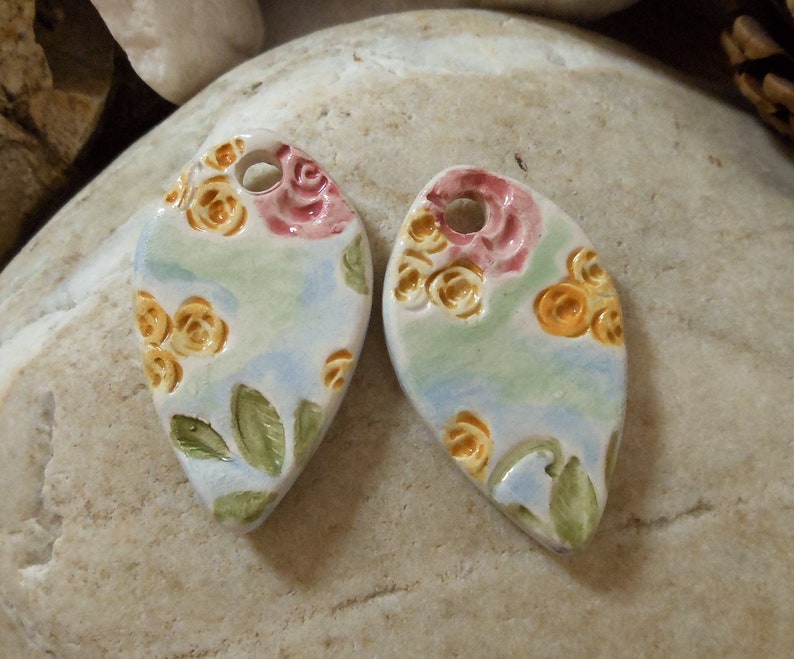 on green and blue background shape drops Set of two ceramic pendants pink and yellow floral motif