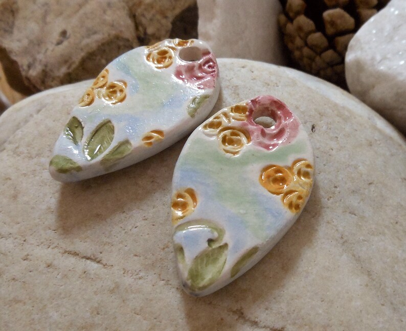 on green and blue background shape drops Set of two ceramic pendants pink and yellow floral motif