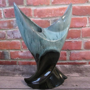 Peut inclure: Un vase en céramique moderne du milieu du siècle avec un design sculptural unique. Le vase présente un glaçage bicolore, avec une section supérieure turquoise et grise et une base noire brillante. Le vase a une forme torsadée et organique.