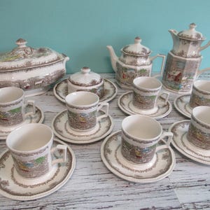 May include: A vintage tea set with a brown and white floral pattern. The set includes a teapot, creamer, sugar bowl, and six teacups and saucers.