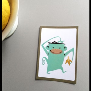 Carte de singe, carte postale aux couleurs vives avec le singe et la banane, dans les couleurs blanches, brunes et turquoise