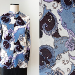 May include: A long-sleeved shirt with a white background and a paisley pattern in shades of blue, purple, and brown.