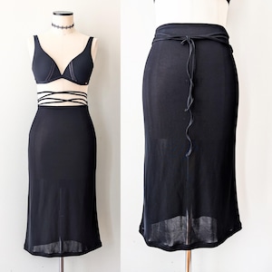 Peut inclure: Une jupe maxi noire en voile avec un ruban noir noué à la taille.