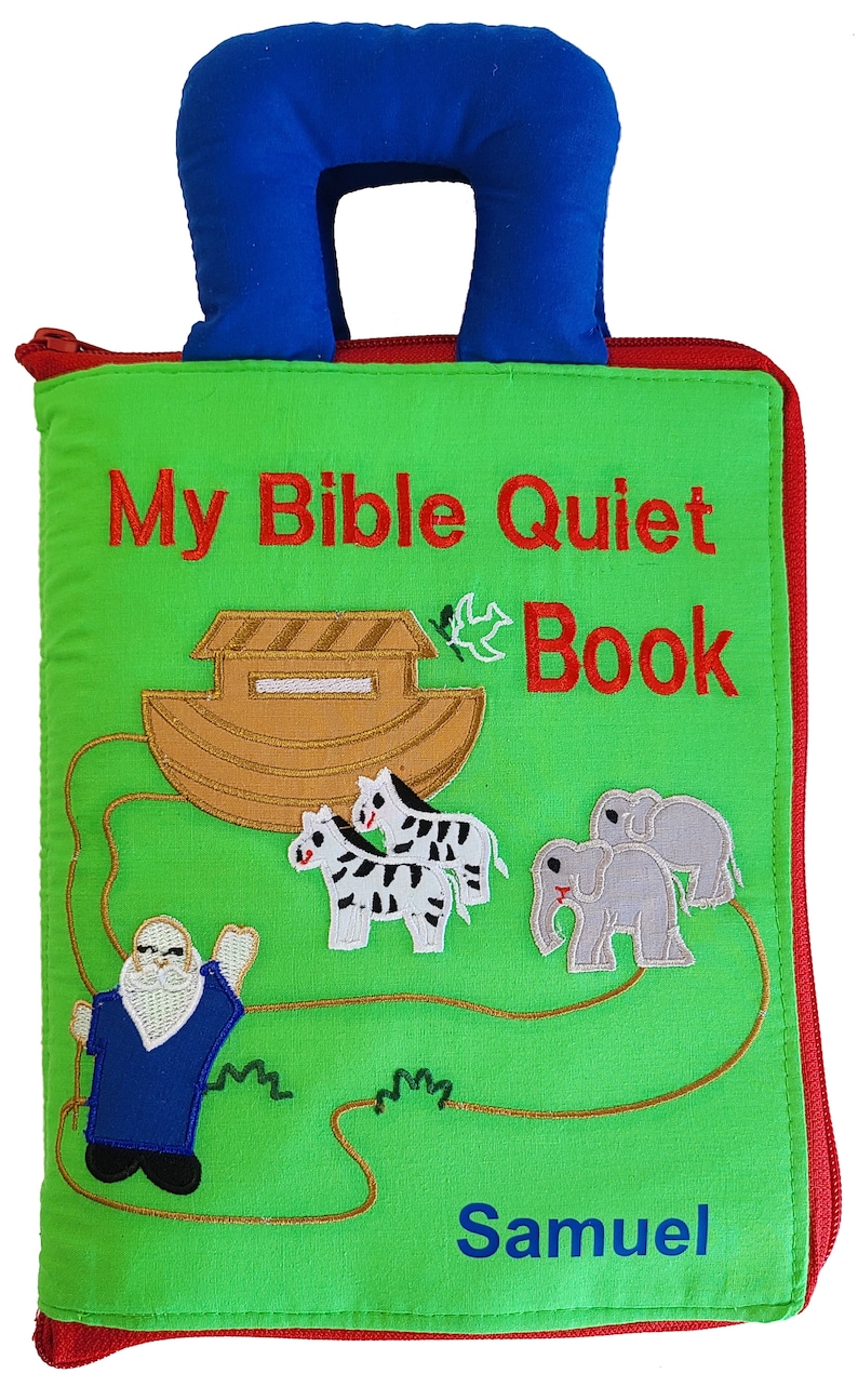 May include: A green fabric quiet book with a blue handle. The front cover features a brown ark with a white dove, two zebras, two elephants, and a man with a white beard. The text "My Bible Quiet Book" is embroidered in red and the name "Samuel" is embroidered in blue.