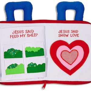 May include: A red and white felt book with blue handles. The book has two pages, one with the text "Jesus Said Feed My Sheep" and four green felt patches, and the other with the text "Jesus Said Show Love" and a large red felt heart with a pink felt heart and a red and white checkered heart inside.