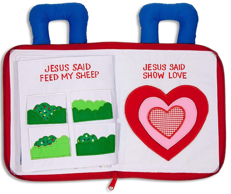 May include: A red and white felt book with blue handles. The book has two pages, one with the text "Jesus Said Feed My Sheep" and four green felt patches, and the other with the text "Jesus Said Show Love" and a large red felt heart with a pink felt heart and a red and white checkered heart inside.