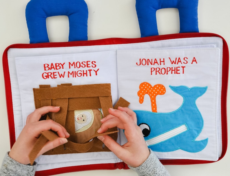 May include: A felt book for children with two pages. The left page has a brown felt basket with a baby inside and the text "Baby Moses Grew Mighty". The right page has a blue felt whale with the text "Jonah Was A Prophet".