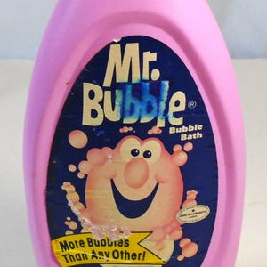 May include: A pink plastic bottle of Mr. Bubble Bubble Bath. The label features the Mr. Bubble character and the text "More Bubbles Than Any Other!" The bottle contains 16 fl oz (1 pt) of bubble bath.