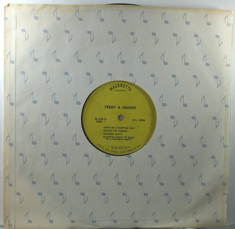 May include: Yellow vinyl record label with the text "Majorette Records" and "Tressy & Cricket" in black. The label also includes the song titles "Going on a Shopping Trip", "Buying the Present", "Glamorous Party", "Planning What to Wear to a Birthday Party", and the record number "M-308-A, Side 1" and "33 1/3 RPM".