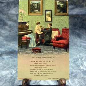 May include: A vintage postcard featuring an illustration of a parent and child in a green room with a piano, red sofa, and red armchair. The text reads: KISS DADDY GOOD-NIGHT! (1). Tell me who loves you, my fairy elf, Daddy, your daddy.