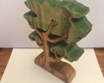 May include: A wooden tree toy with a green painted trunk and branches. The tree is made of multiple pieces of wood that are joined together.