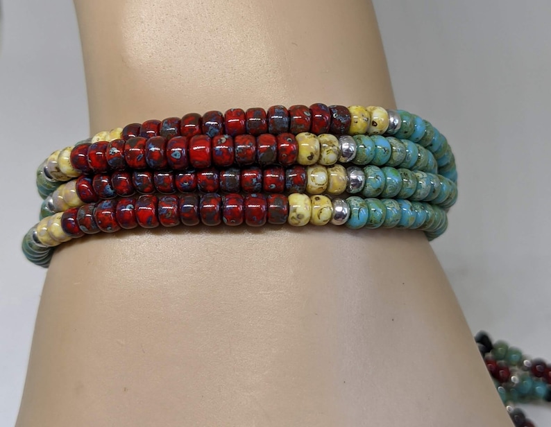 May include: Multi-colored beaded bracelet with red, yellow, and blue beads. The bracelet is made of small, round beads and is layered to create a unique and colorful design.