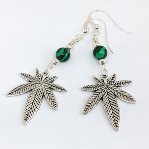 May include: Silver earrings with green malachite beads and a silver marijuana leaf design.