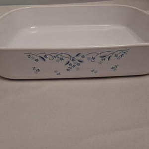 May include: White rectangular baking dish with rounded corners and handles. The dish is decorated with a blue floral pattern along the rim. A classic kitchenware item for baking and serving.
