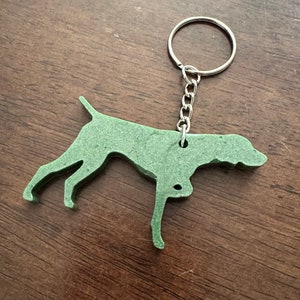 May include: Green German Shorthaired Pointer dog silhouette keychain with a silver metal key ring.
