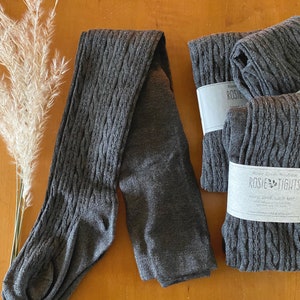 May include: Grey cable knit tights with a hand-dyed, cable knit design. Rosie Creek Boutique Rosie Tights Hand-dyed, Cable Knit 100%  Recycled  Nylon  www.rosiecreekboutique.etsy.com