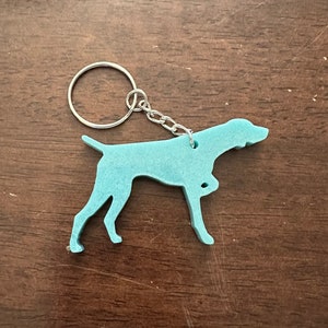 May include: A light blue German Shorthaired Pointer dog keychain with a silver key ring and chain.