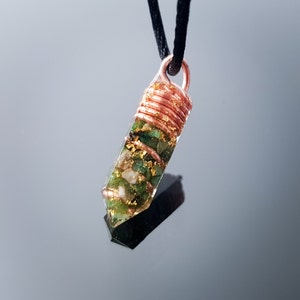 May include: A copper wire wrapped pendant with a clear resin point filled with green and white stones and gold flakes.