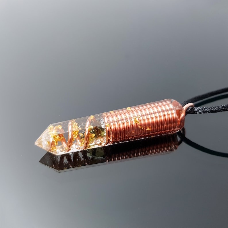 May include: A copper wire wrapped around a clear crystal pendant with gold flecks. The pendant is attached to a black cord.
