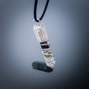 May include: Silver wire wrapped pendant with clear quartz, black tourmaline, and green aventurine crystals.