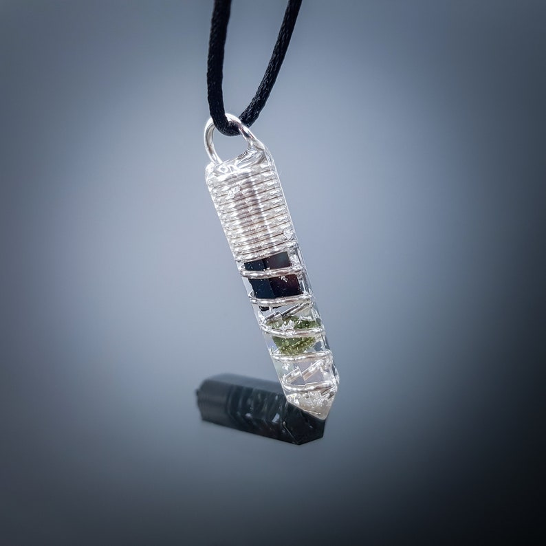 May include: Silver wire wrapped pendant with clear quartz, black tourmaline, and green aventurine crystals.