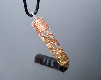 May include: A clear quartz crystal pendant with copper wire wrapped around it. The crystal is filled with gold flakes and has a black cord.