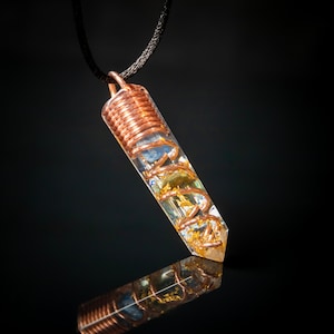 May include: A clear crystal pendant with gold flakes and copper wire wrapped around it. The pendant is attached to a black cord.