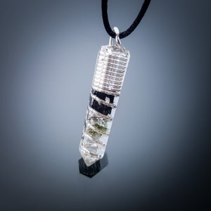 May include: A silver wire wrapped clear quartz crystal pendant with green and black inclusions. The pendant is hanging from a black cord.