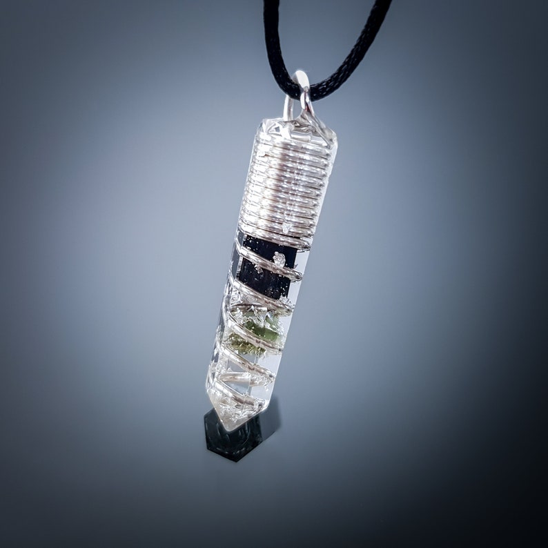 May include: A silver wire wrapped clear quartz crystal pendant with green and black inclusions. The pendant is hanging from a black cord.