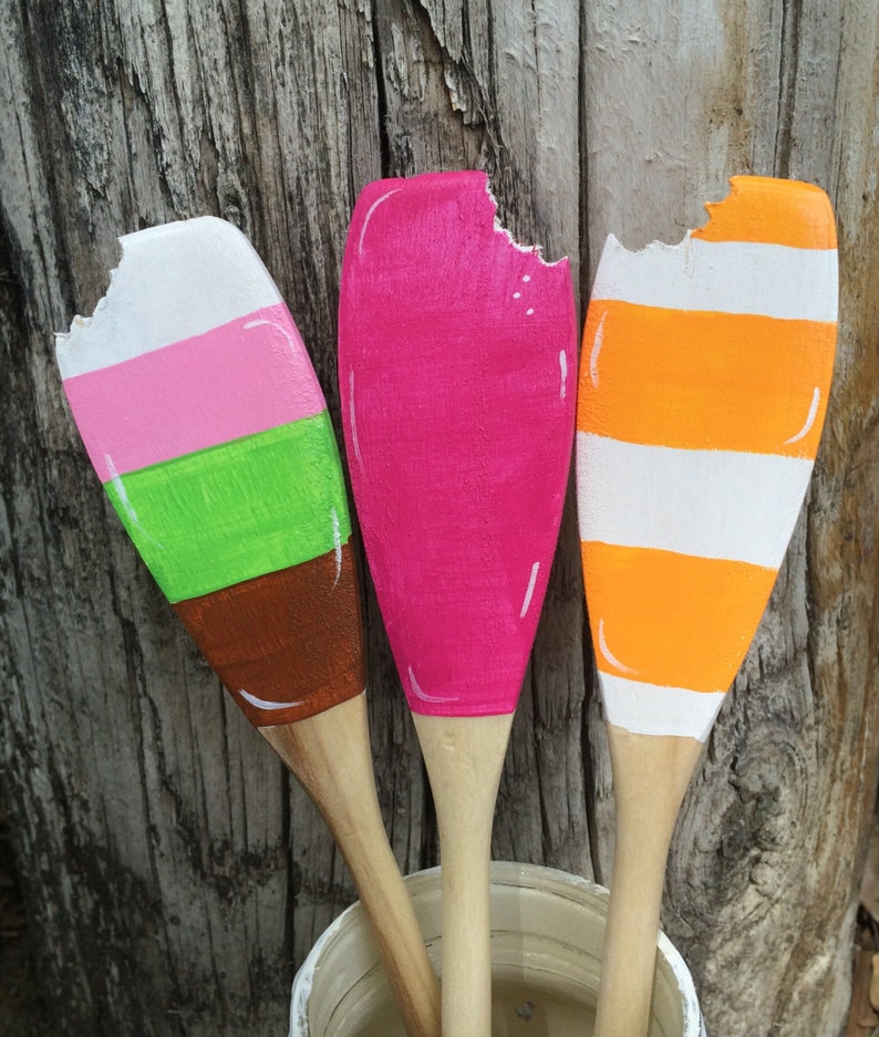 Puede incluir: Tres cucharas de madera pintadas para parecer paletas de helado. Las cucharas est&aacute;n pintadas de rosa, naranja y verde y rayas blancas. Las cucharas est&aacute;n dispuestas en una fila con la cuchara rosa en el medio.