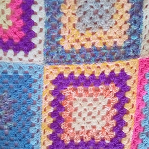 May include: A colorful crocheted blanket made of squares in various shades of blue, pink, purple, and yellow.