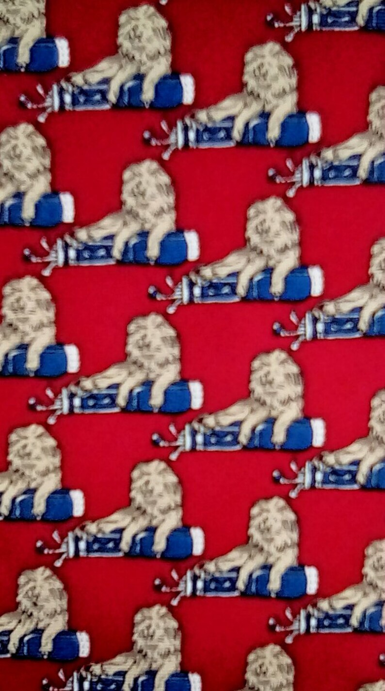 May include: A red fabric with a repeating pattern of white lions sitting on blue golf bags. The lions are facing right and have a playful expression.