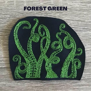 May include: A dark blue fabric patch with a green embroidered design of three stylized plants with swirling tendrils. The text "FOREST GREEN" is printed above the design.